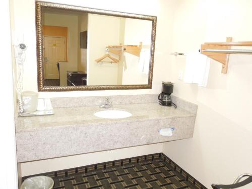 a bathroom with a sink and a mirror at Homegate Inn & Suites West Memphis in West Memphis