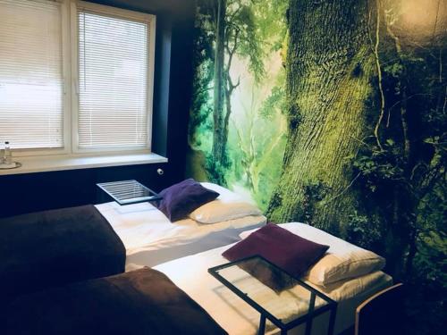 a bedroom with two beds and a tree mural at Hotel Szablewski in Dymaczewo Nowe