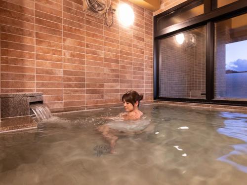 a woman in a jacuzzi in a hot tub at Central Hotel Takeoonsen Ekimae in Takeo