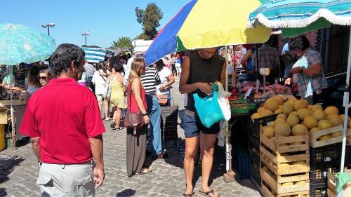 a group of people walking around a market with an umbrella at Apartamento Parque Ria Formosa, Olhão in Olhão