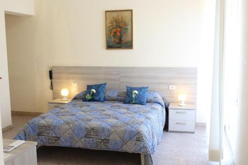 a bedroom with a bed with blue pillows and two tables at Hotel Luca in Lido di Camaiore