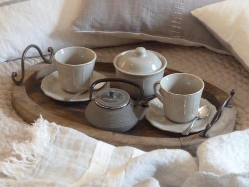 a tray with two cups and a tea set on a bed at La Couette de l'Ours in Aywaille