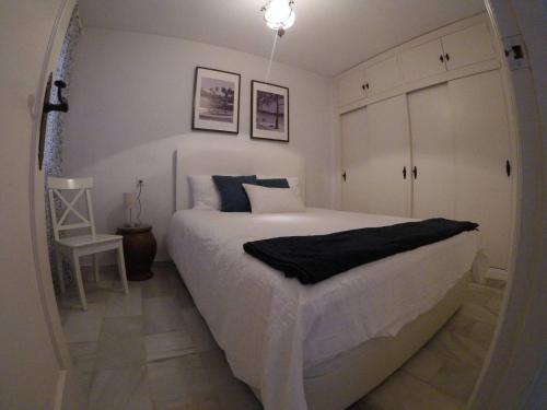 sypialnia z dużym białym łóżkiem i krzesłem w obiekcie holidays in pueblo evita w mieście Benalmádena