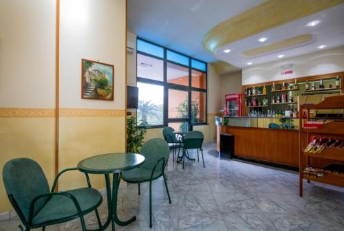 un restaurante con sillas y mesas verdes y un bar en Hotel Venere, en Villaricca