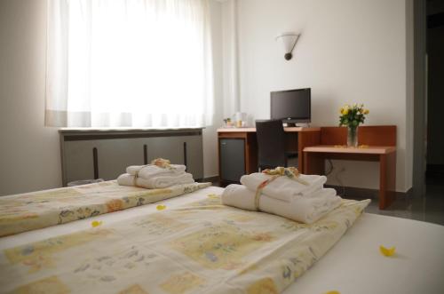 two beds with towels on them in a room at Hotel Bahnhof Haus in Chiasso