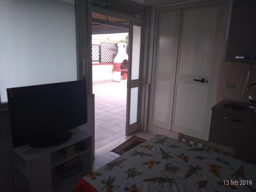 a room with a television and a door to a patio at Casa vacanza Leone con Terrazza in Ginosa Marina