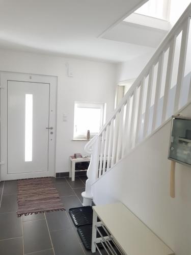 a white hallway with a staircase and a white door at Bogi's Ferienhaus - Pension in Laakirchen