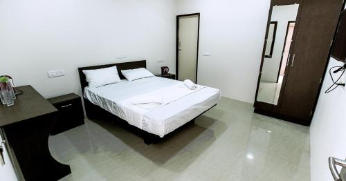 1 dormitorio con cama blanca y espejo en Indra Regency, en Tiruttani
