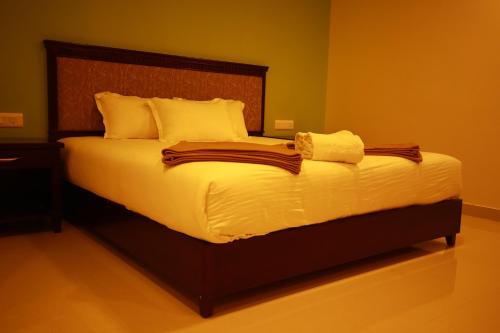 a bedroom with a large bed with white sheets and pillows at Temple Plaza Kochi in Chottanikara