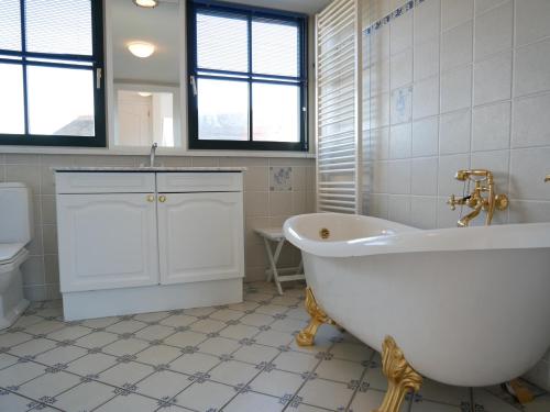 een witte badkamer met een bad en een toilet bij Villa Buiten 53 in Callantsoog