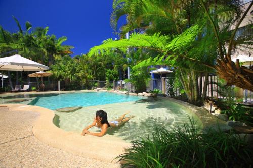 a woman is laying in a swimming pool at Portobello By The Sea in Caloundra