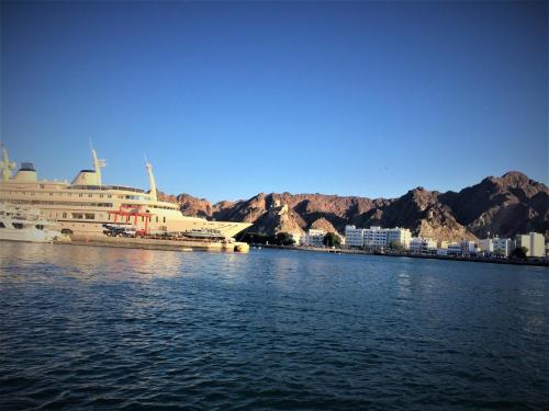 un crucero atracado en un puerto con montañas al fondo en NASEEM HOTEL, en Mascate