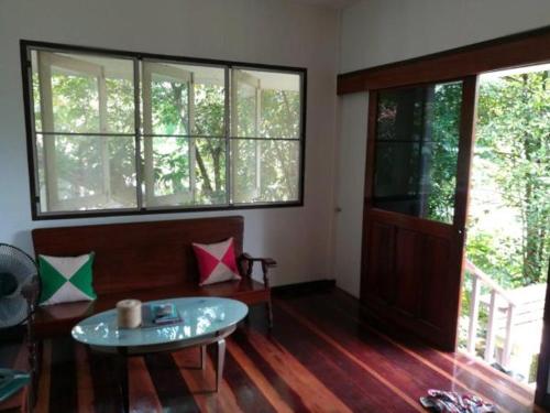 a living room with a table and some windows at Water's House in Suratthani