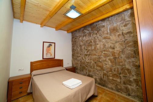 um quarto com uma cama e uma parede de pedra em Apartamento Olmeda em Alcalá del Júcar