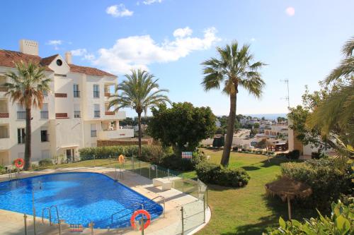 una gran piscina frente a un edificio con palmeras en Miraflores Golf Gardens II Luxe Appartement at Riviera del Sol, en Mijas Costa