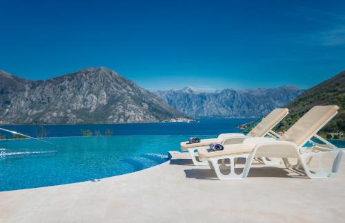 two lounge chairs sitting on the edge of a swimming pool at Lavender Bay Apartment in Donji Morinj