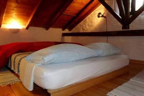 a white bed in a room with a wooden floor at Traditional Greek Cottage in Palaiókastron