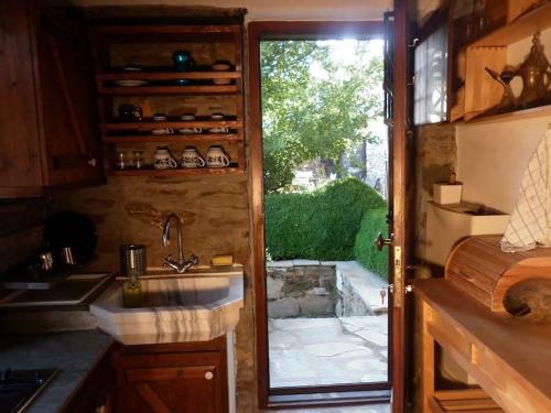 cocina con fregadero y puerta corredera de cristal en Traditional Greek Cottage, en Palaiókastron