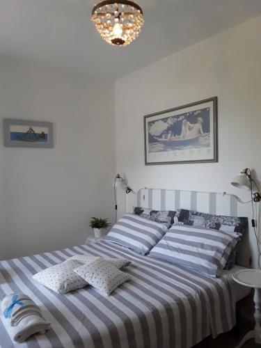 a white bedroom with a large bed with striped sheets at Prima Fila in Lerici