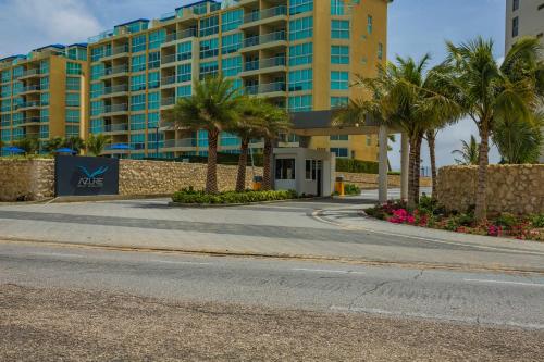 a street in front of a large building with palm trees at Azure Beach Residences in Palm-Eagle Beach