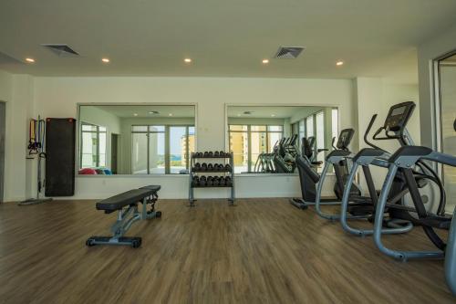 a gym with several treadmills and ellipticals and mirrors at Azure Beach Residences in Palm-Eagle Beach
