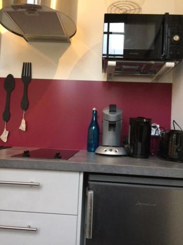 un comptoir de cuisine avec des ustensiles sur un mur rouge dans l'établissement LE CID, à Saumur