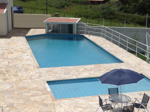a swimming pool with a table and an umbrella at Pousada Canto dos Canários in Socorro