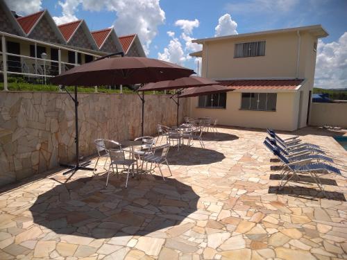 a patio with chairs and tables with umbrellas at Pousada Canto dos Canários in Socorro