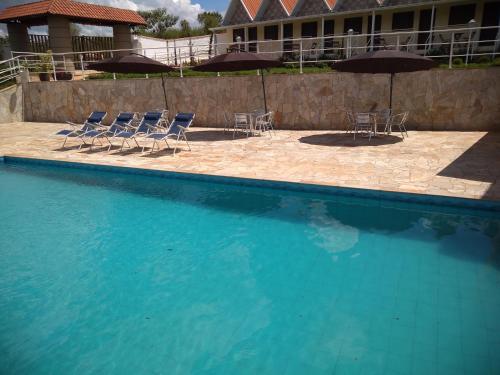 a swimming pool with chairs and umbrellas next to a building at Pousada Canto dos Canários in Socorro