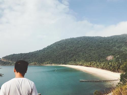 a man standing on a cliff looking at a beach at Sunbay Homestay Cu Lao Cham in Tân Hiệp