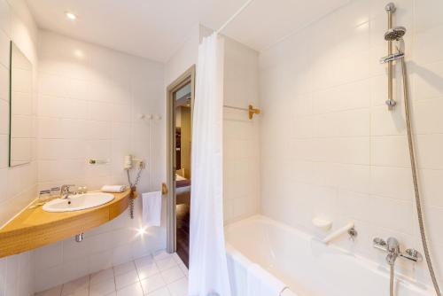 a white bathroom with a tub and a sink at Hôtel Val de Poix- Logis Hôtel Restaurant in Saint-Hubert