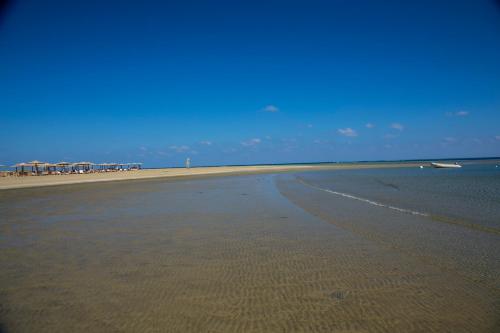 an empty beach with a boat in the water at Lahami Bay Beach Resort in Abū Ghuşūn