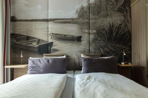 a bedroom with two beds and a painting of a boat at Hotel am Untersee in Bantikow