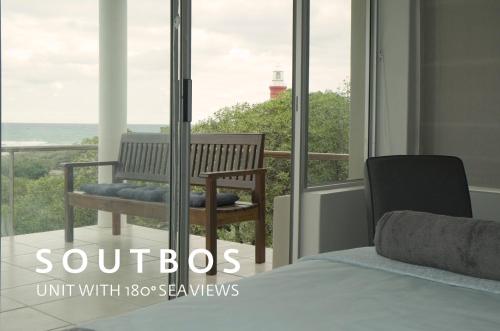 a bedroom with a bench and a view of the ocean at Soutbos & Janfrederik in Agulhas