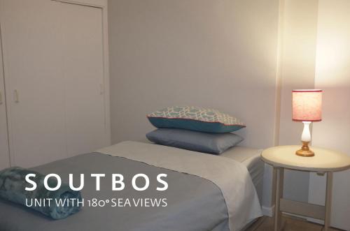 a small bedroom with a bed and a table with a lamp at Soutbos & Janfrederik in Agulhas