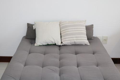 a gray couch with a pillow on top of it at Búzios Lofts in Búzios