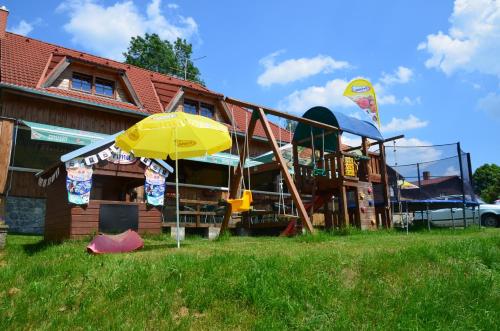 a house with a playground and an umbrella at EDER- Penzion & Apartmány in Horní Planá