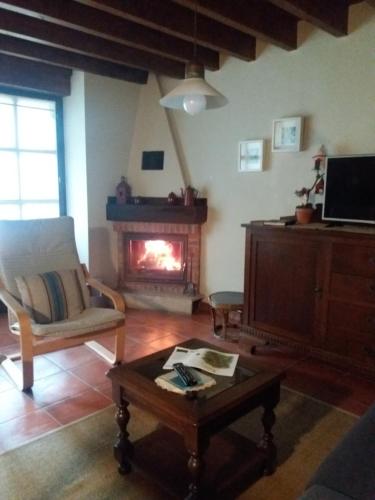 ein Wohnzimmer mit einem Kamin, einem Stuhl und einem Couchtisch in der Unterkunft El Acebo in Infiesto