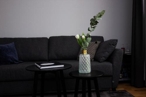 a living room with a couch and two tables with a vase at Livin Station Hotel in Örebro