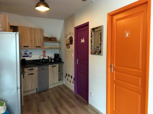 a kitchen with an orange and purple door in it at La Seine en couleurs in Duclair