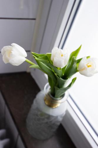 a vase filled with white flowers sitting on a table at Hotell Hjalmar in Örebro