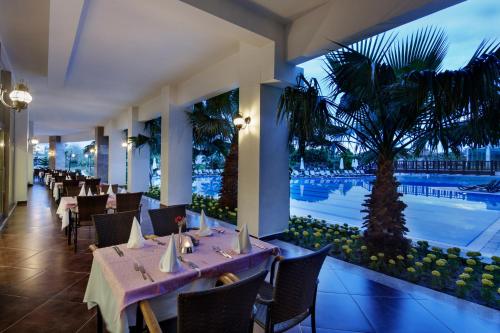 een restaurant met tafels en stoelen en een zwembad bij Alba Royal Hotel - Ultra All Inclusive -Adults Only (+16) in Side