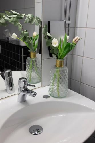 a bathroom sink with two vases with flowers on it at City Central Hotel Örebro by First Hotels in Örebro