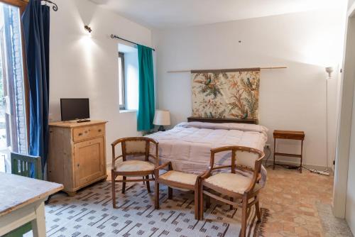 a bedroom with a bed and two chairs and a television at Pescalina - Pescate in Pescate