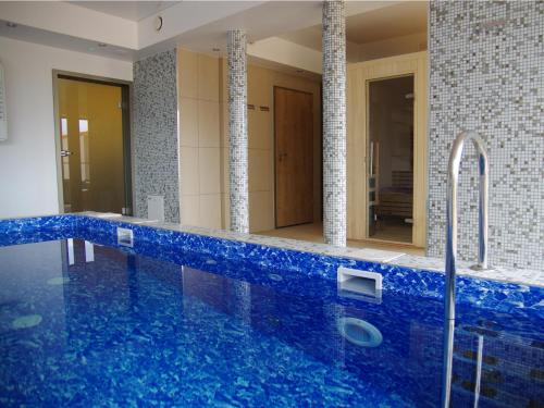 La salle de bains est pourvue d'une baignoire bleue avec un miroir. dans l'établissement Hotel Uniejów, à Uniejów