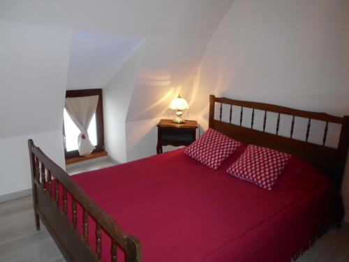um quarto com uma cama vermelha e um candeeiro sobre uma mesa em La petite maison em Tauves