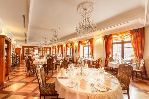 een eetkamer met tafels en stoelen en een kroonluchter bij Rezydencja Dwór Polski in Bełchatów