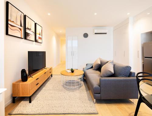 a living room with a couch and a flat screen tv at Artel Apartments Brunswick in Melbourne