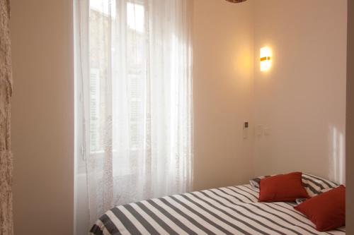 a bedroom with a bed with red pillows and a window at Le Moulin de PEBRE in La Ciotat
