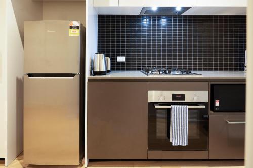 a kitchen with a refrigerator and a stove at Artel Apartments Brunswick in Melbourne